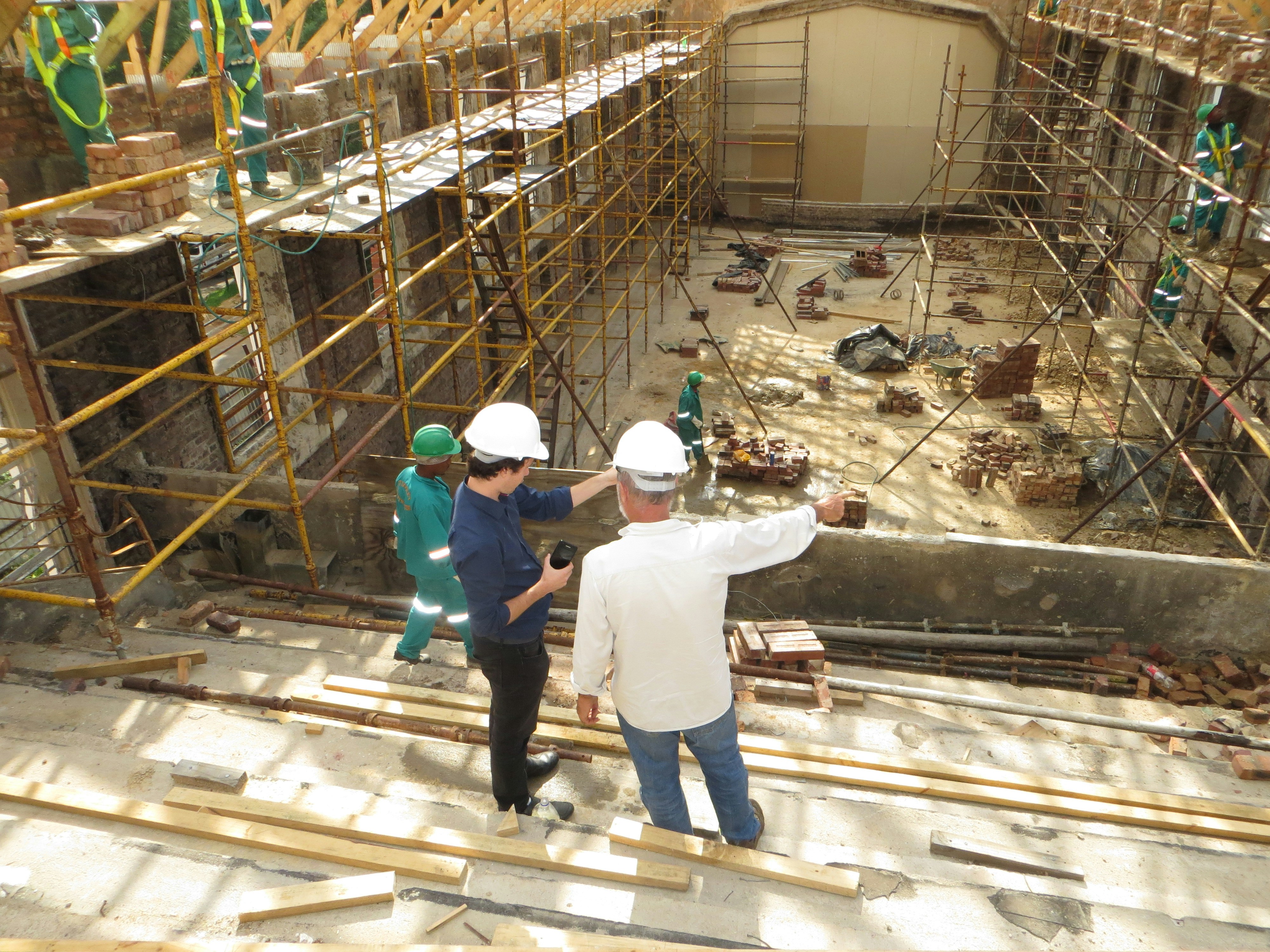 Two construction workers standing in a fire-damaged building examining plans
